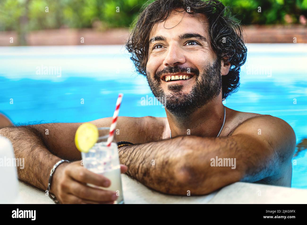 Portrait of a hairy man relaxing by drinking a refreshing cocktail and chatting with friends while taking a bath in the pool - concept of summer vacat Stock Photo