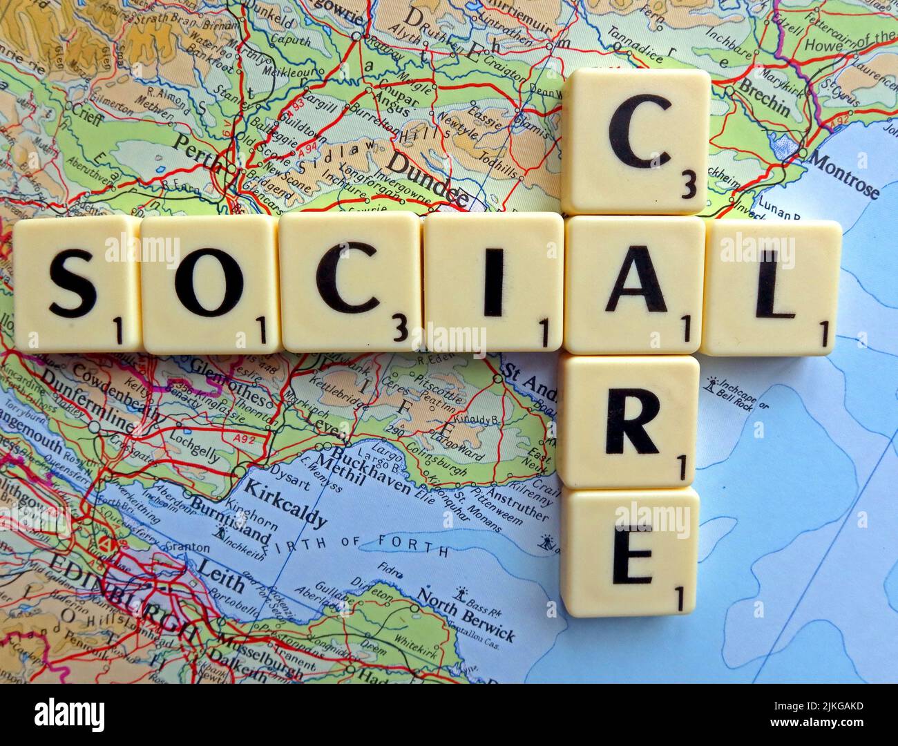 The words “Social Care” spelt with tiles on a map of Central Scotland, illustrating Scottish care policy devolved responsibilities & Andy Burnham push Stock Photo