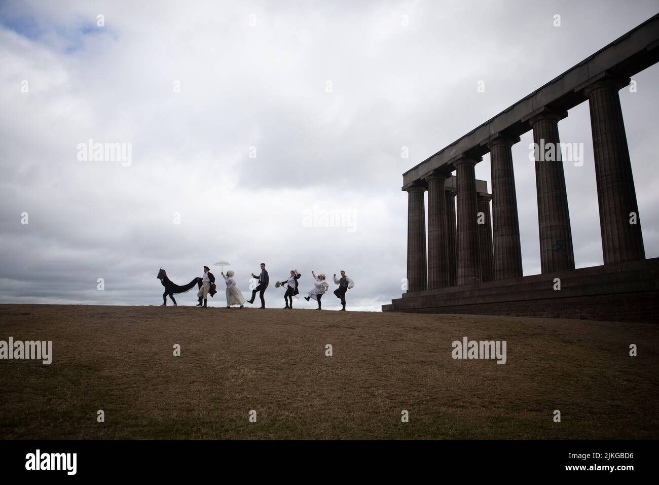 Edinburgh. Scotland. UK. 2nd August 2022. Photocall: Literary closing and slapstick on Calton Hill. The Fringe the six actors from the brilliantly fast paced slapstick romp Classic! (daily 3- 29 August Pleasance 1) will wear a smorgasbord of 17th, 18th, and 19th century costumes (think wigs, parasols, long velvet, military jackets and jolly jack tars). With props including trumpets, parasols, a pantomime horse, very unperiod water pistols and a bright pink melodica). They will be clowning and posing with the city behind them and on The National Monument of Scotland. Pic: Pako Mera/Alamy Li Stock Photo