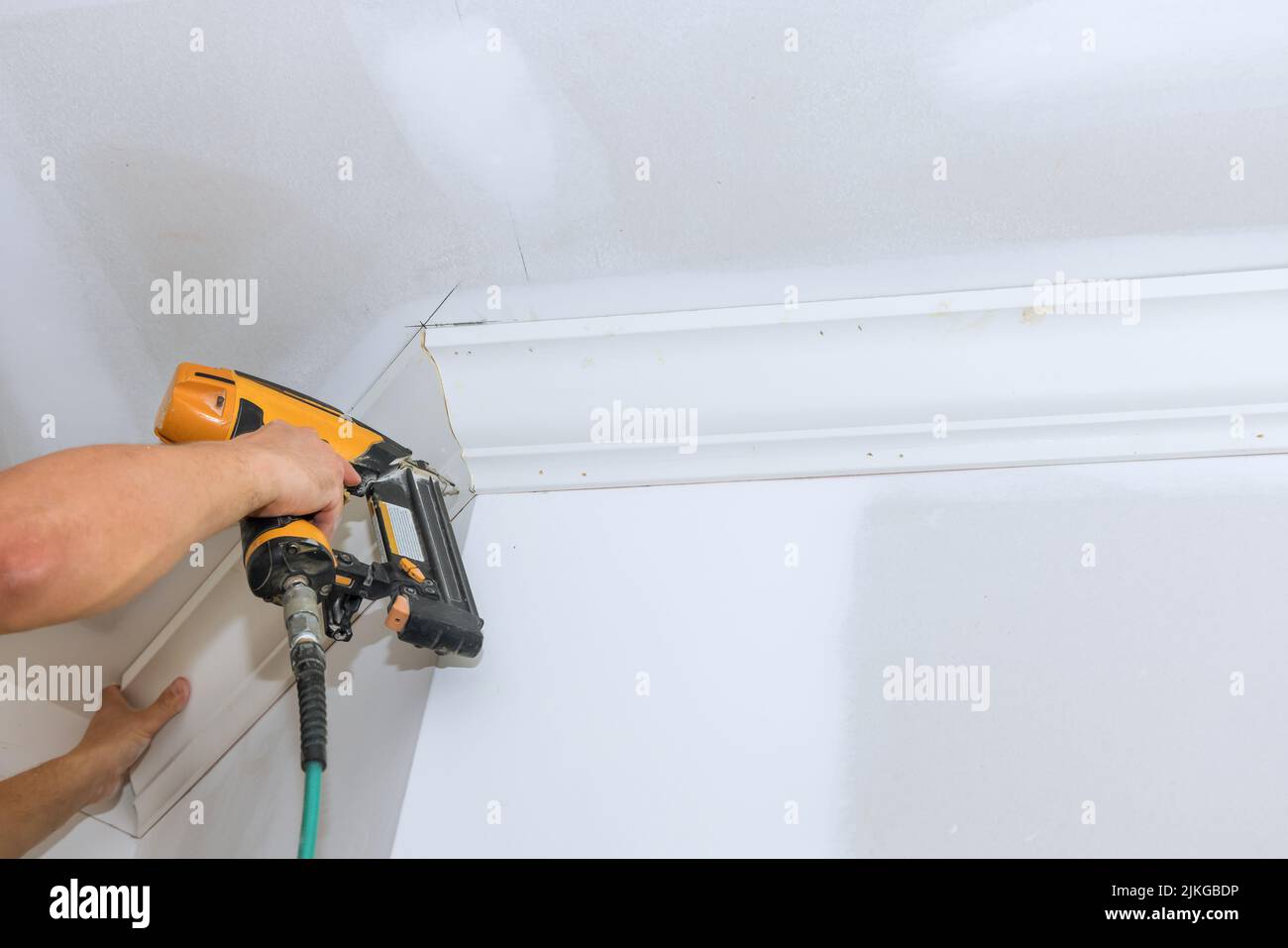 Using an air nail gun, the carpenter installed the crown molding on the