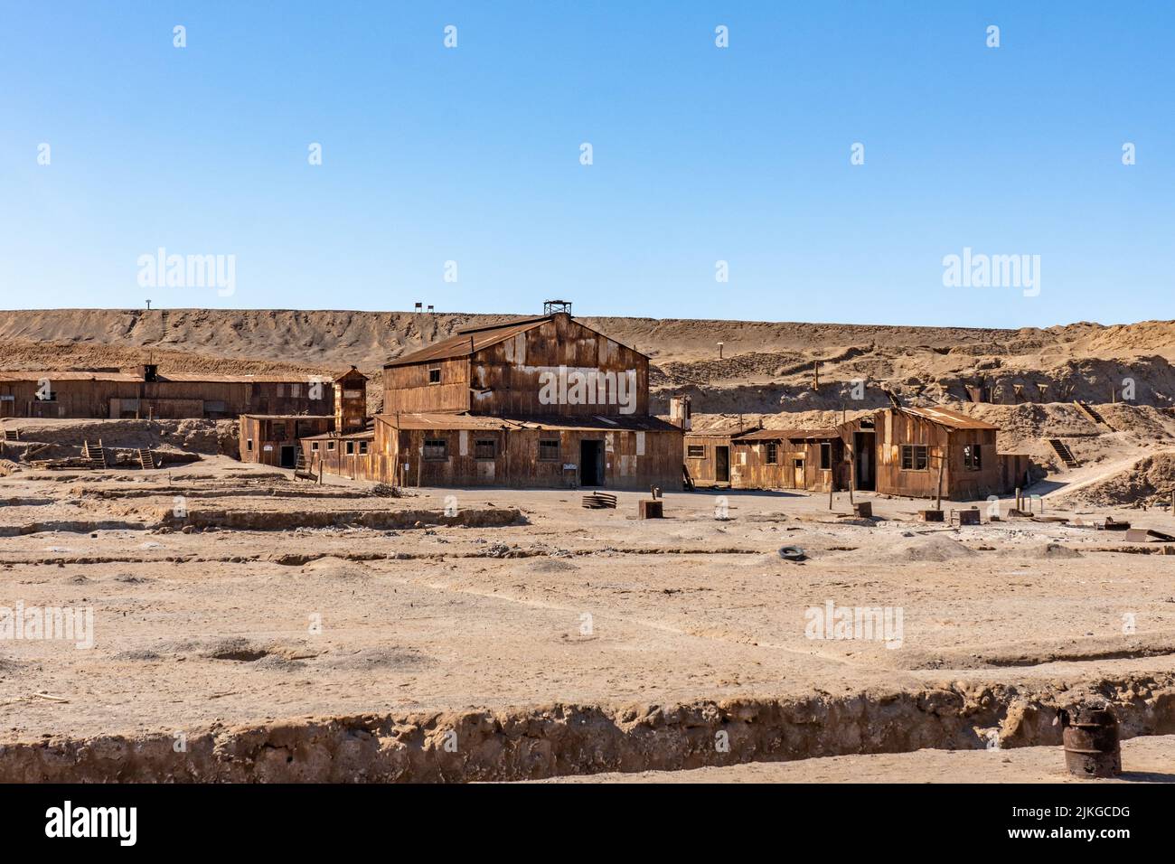Old rusted buildings in front of the tailings pile in the outdoor museum of the saltpeter works at Humberstone, Chile. Stock Photo