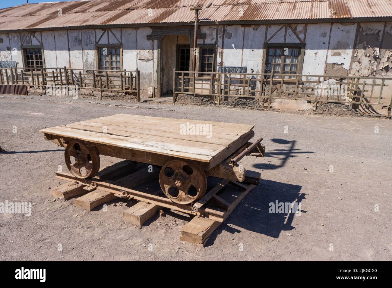 Outdoor museum display of a rail cart used in the saltpeter works in Humberstone, Chile.  Employee housing behind. Stock Photo