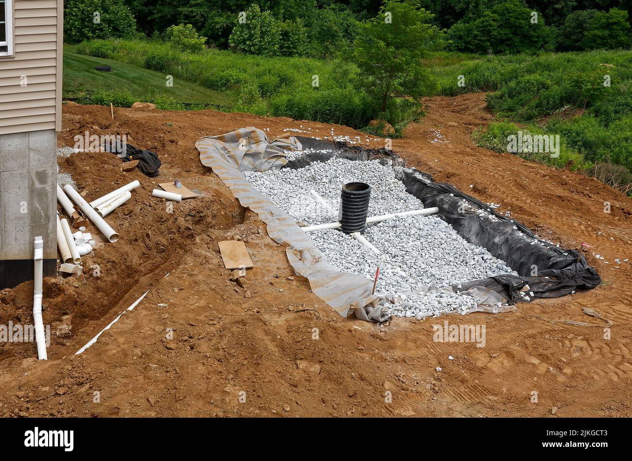 installing runoff drainage behind house, bed of stones, pipes, new construction, dirt, hill, slope, Chester County; PA; Pennsylvania; summer, PR Stock Photo