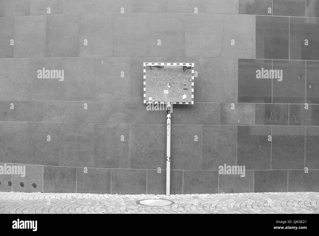 A grayscale of a street mirror in front of a brick wall Stock Photo