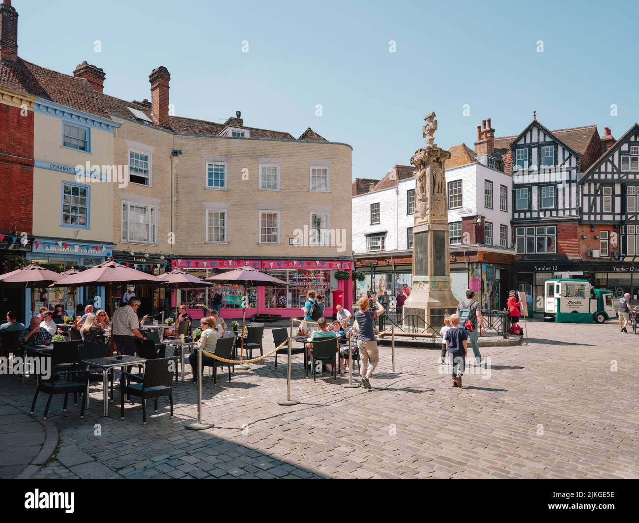 The summer cafes, shops and tourists in Buttermarket Square  at the very heart of Old Canterbury Kent England UK  -  tourism tourists cafes shops Stock Photo
