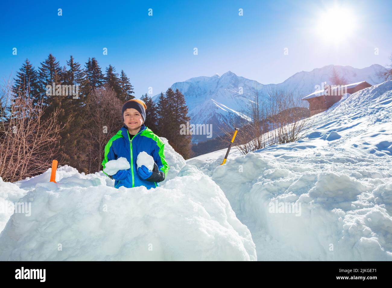 Boy in ski winter outfit prepare snowballs inside snow fortress Stock Photo