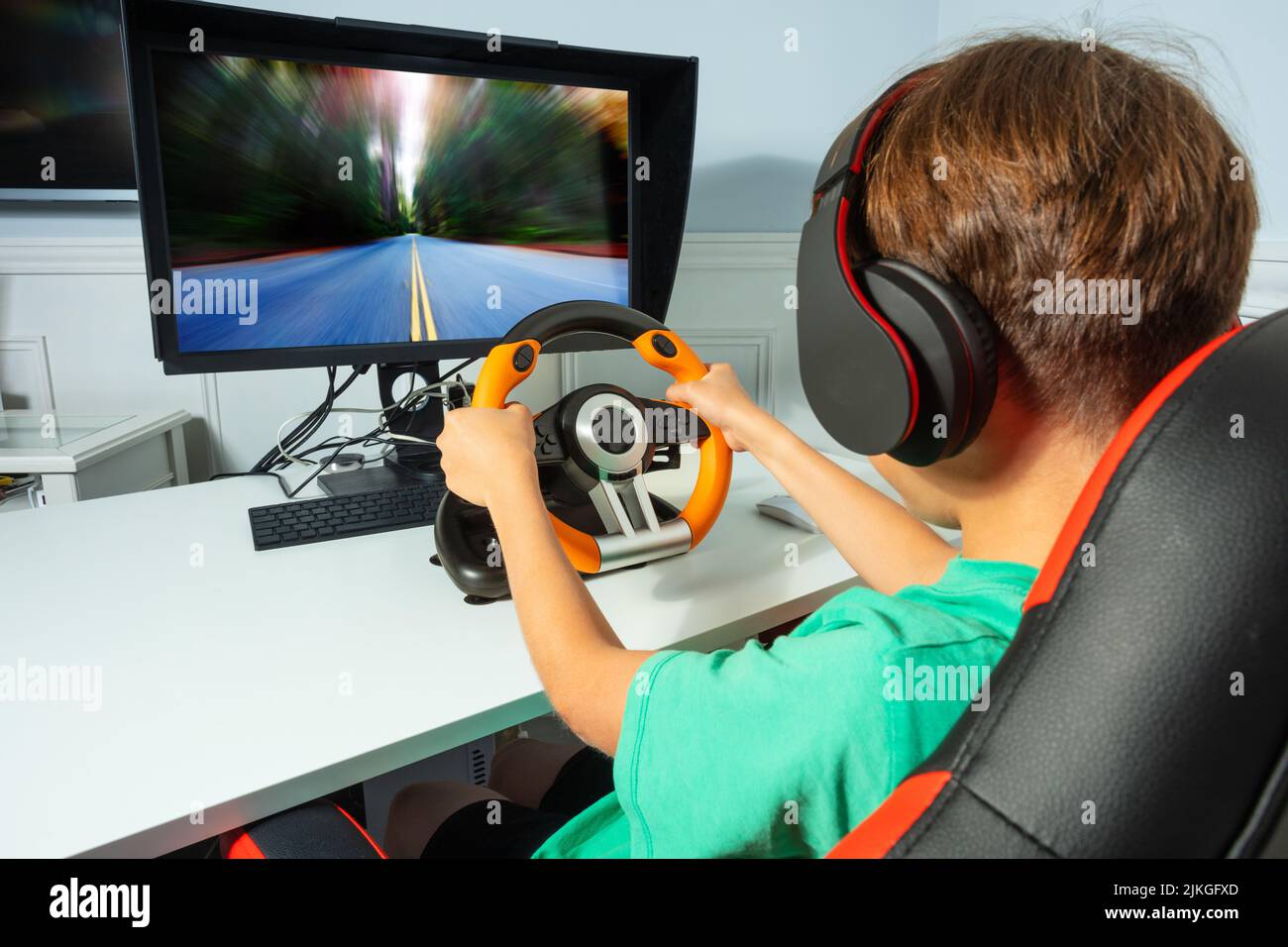 Back view of boy, hands on steering wheel play race game Stock Photo