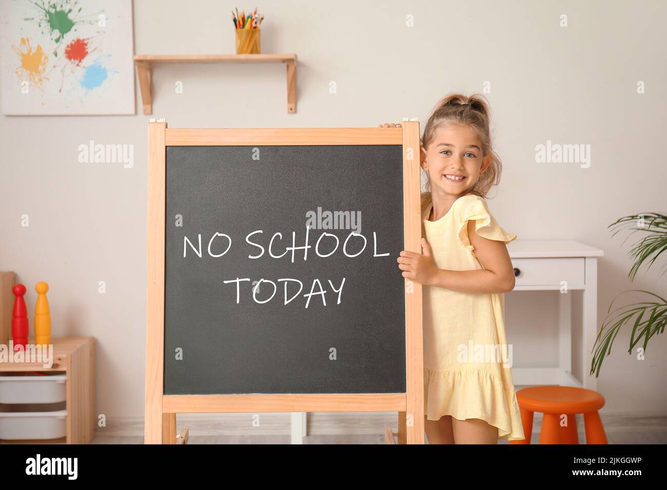 Happy little girl and chalkboard with written text NO SCHOOL TODAY in