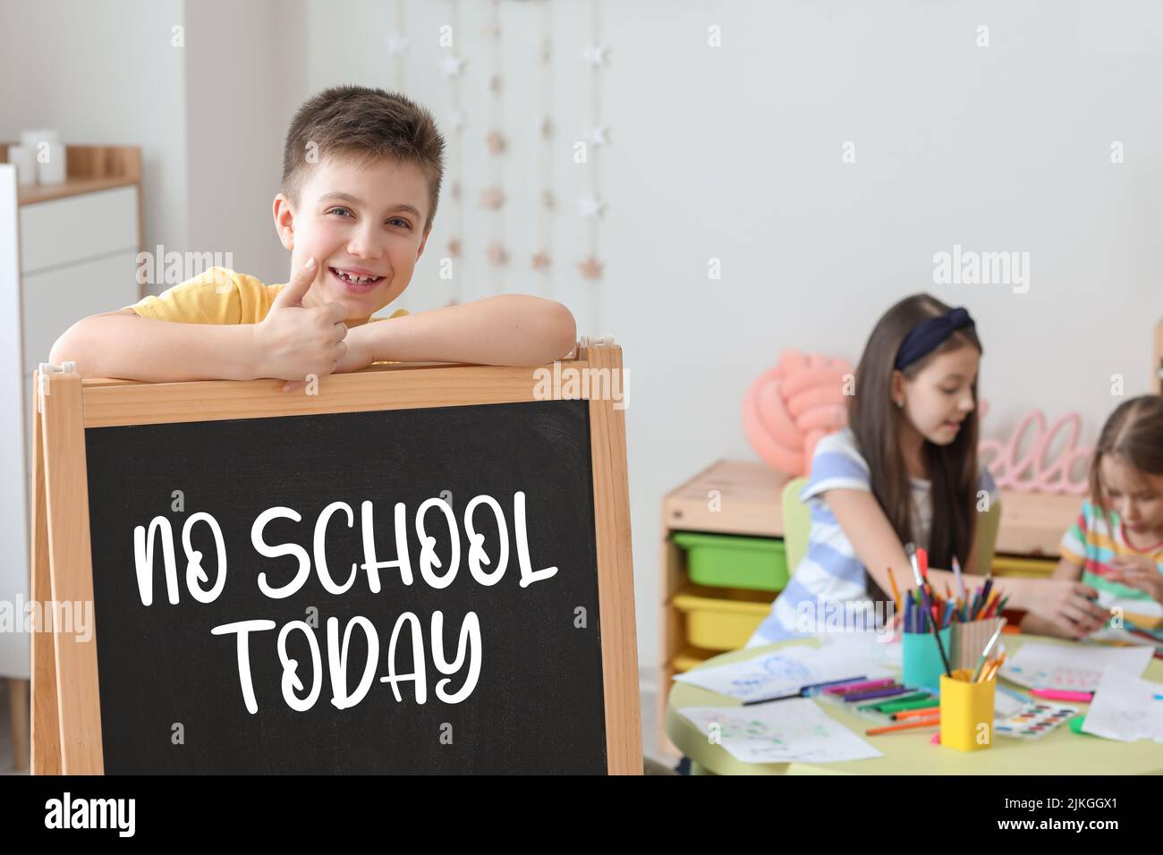 Happy little boy and chalkboard with written text NO SCHOOL TODAY in