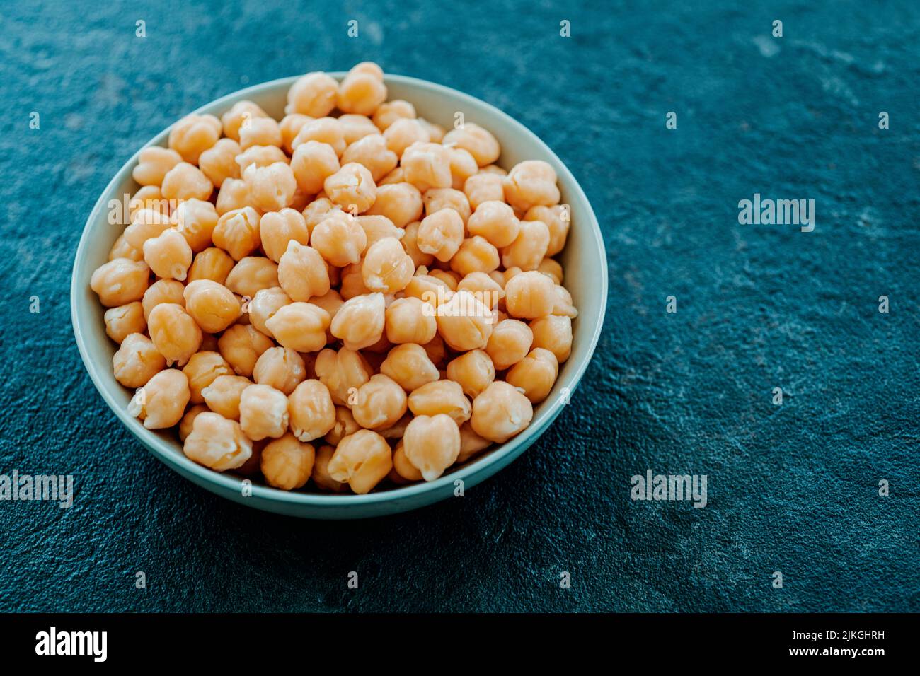 closeup of a ceramic bowl with some cooked chickpeas, on a dark stone surface Stock Photo