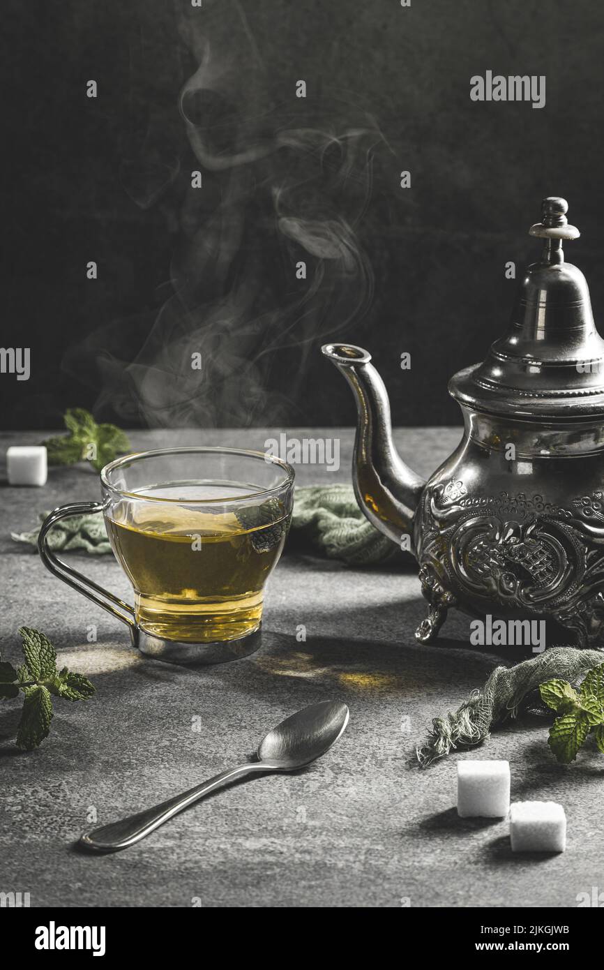 Traditional Moroccan teapot with a steaming cup of tea in a smoky black