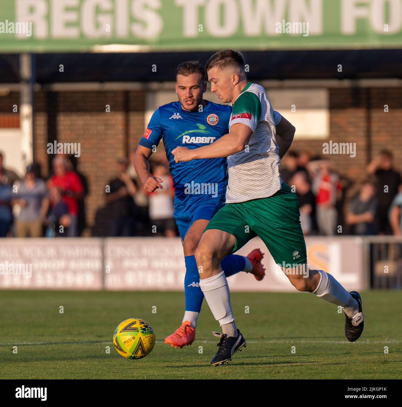 Soccer action a pre-season friendly match between Bognor Regis Town Football Club and Worthing FC. Two players tackle for the ball in front of fans. Stock Photo