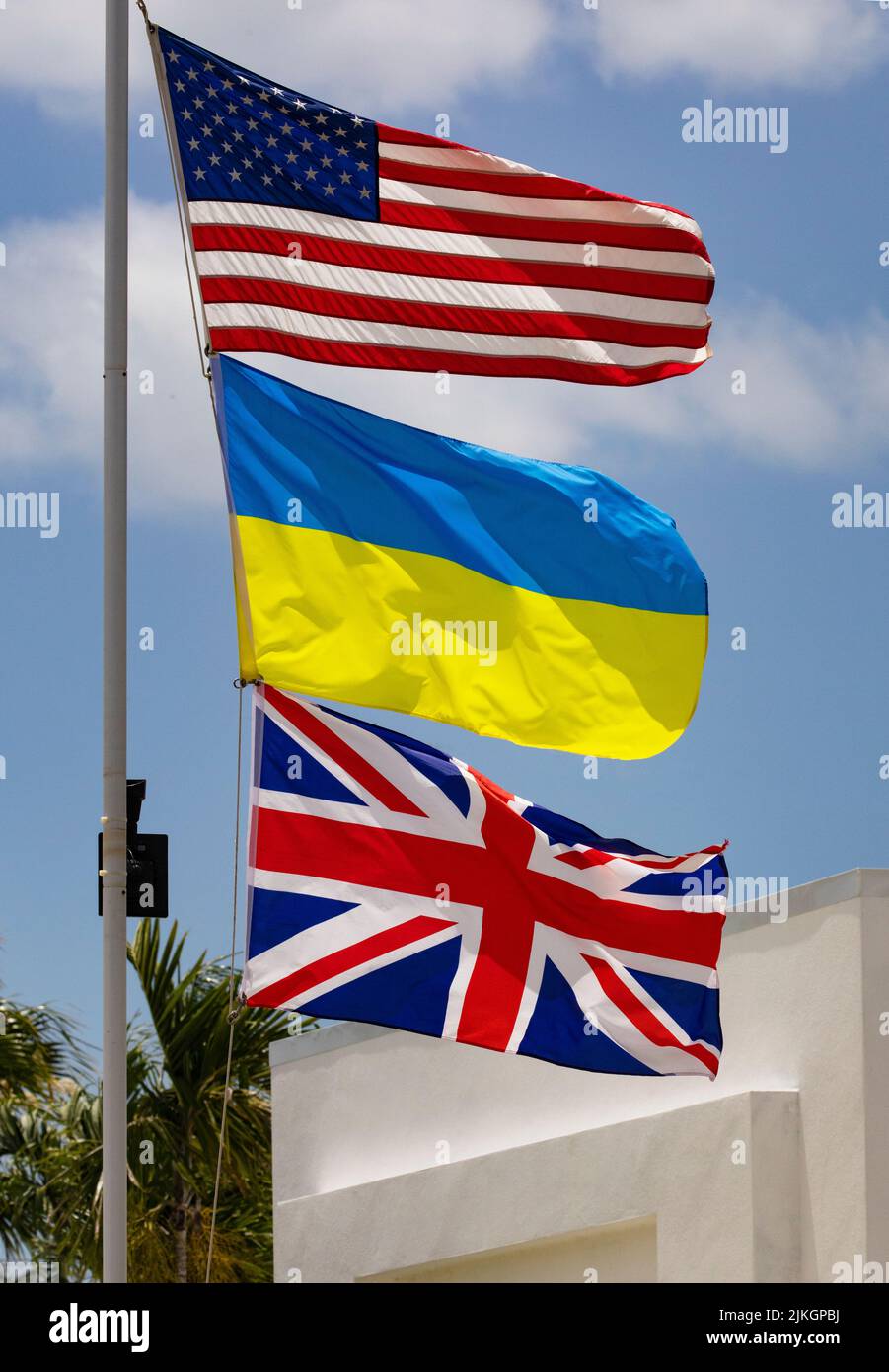 Flags of three nations, United States, Ukraine, and United Kingdom, on white flagpole Stock Photo