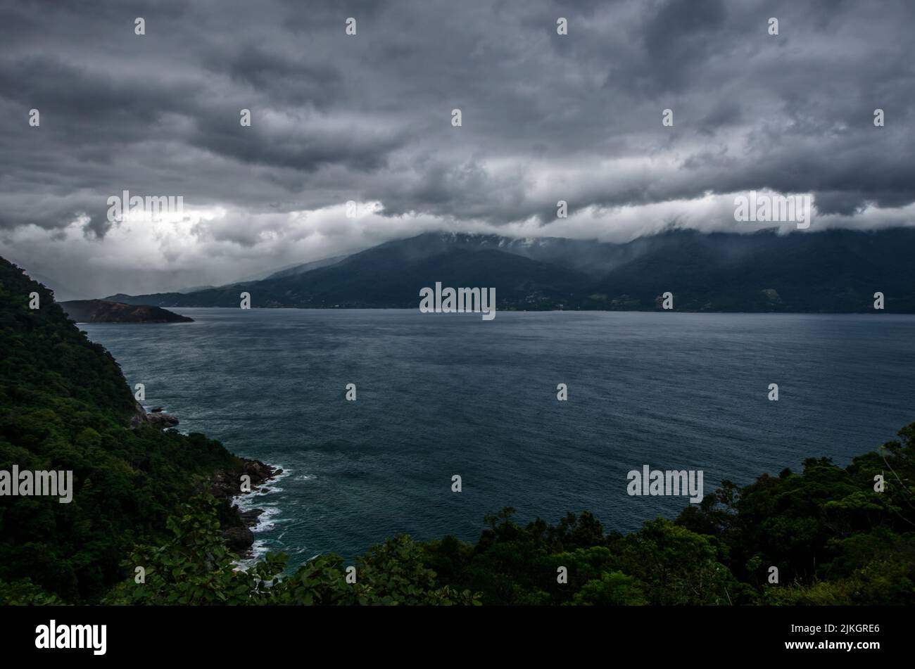 An aerial seascape between mountains under a dramatic cloudy gray sky Stock Photo
