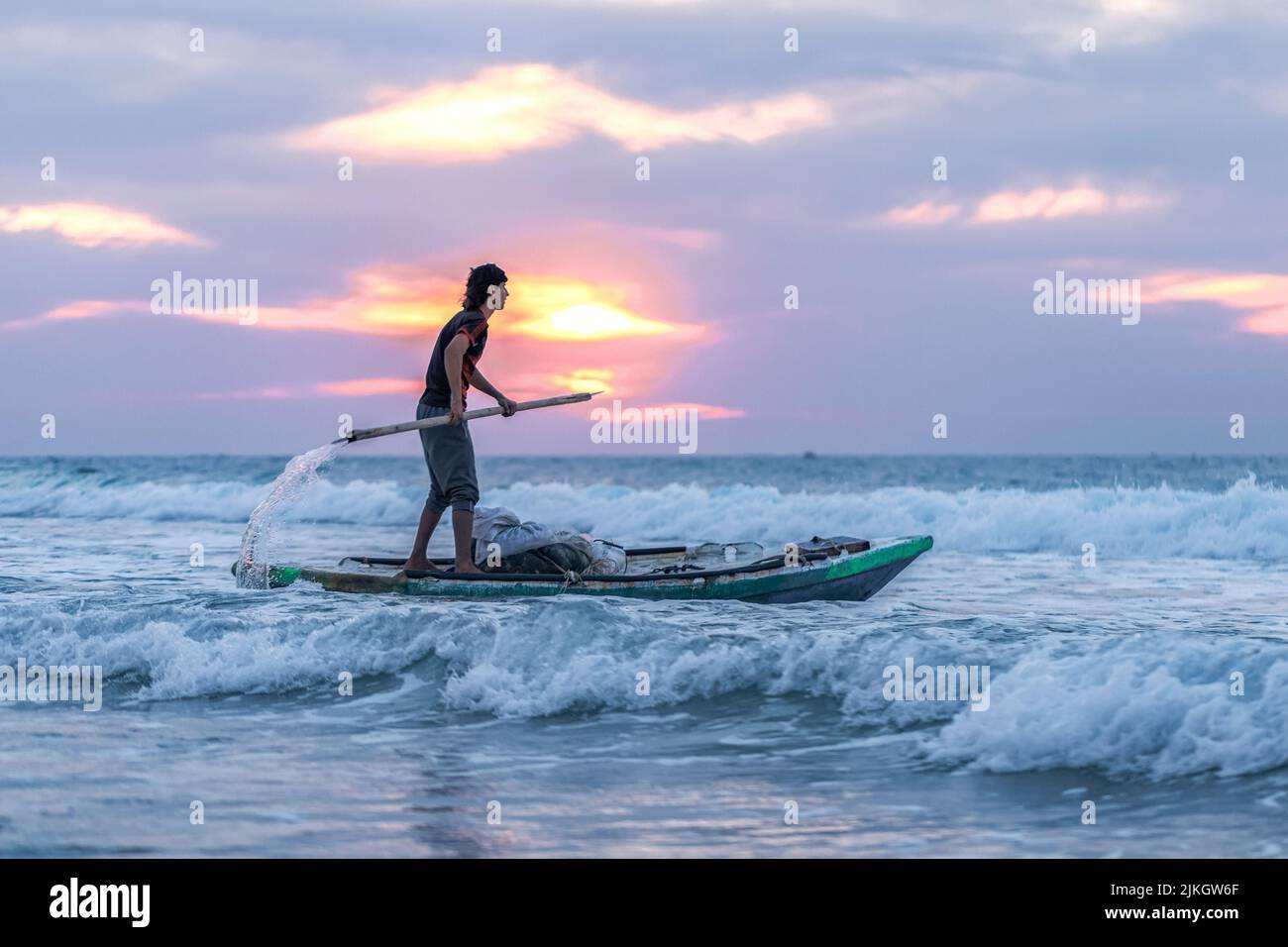 A male paddling on his boat on the sea to catch fish as his livelihood Stock Photo
