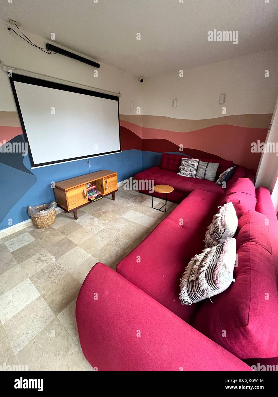 A cozy home theatre room with project screen, sound bar, large couches