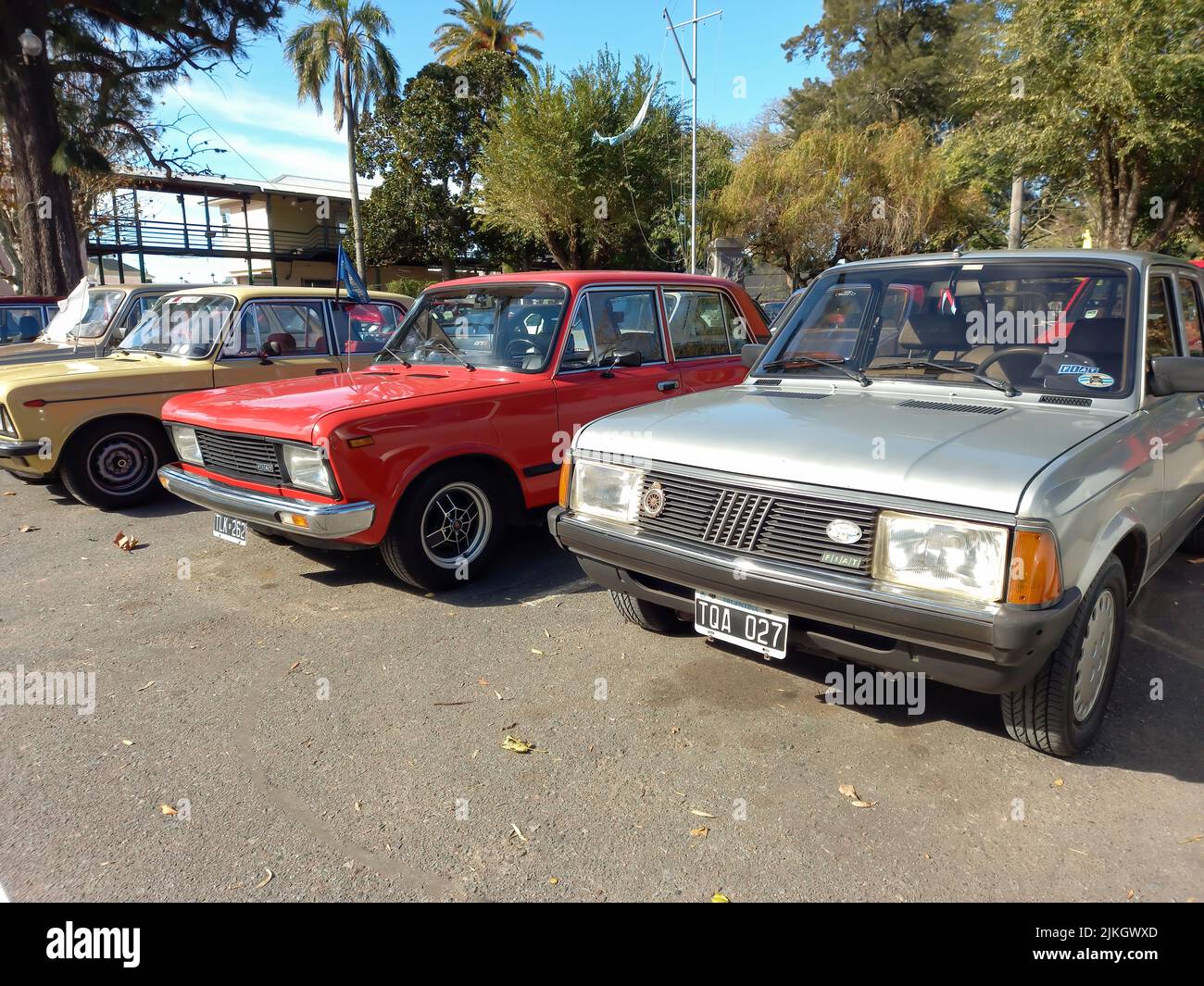 Old red Fiat 128 Europa 1978 - 1982 and gray Super Europa 10983 - 1985 four door sedan in park. Sunny day. Nature, trees. Classic car show. Copyspace Stock Photo
