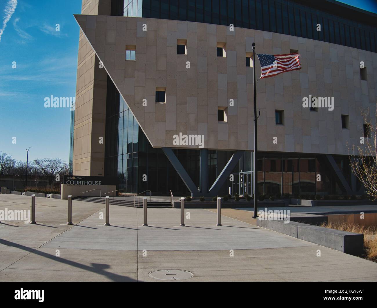 A view of a modern building of a Johnson County Courthouse and a waving flag in Olathe, Kansas