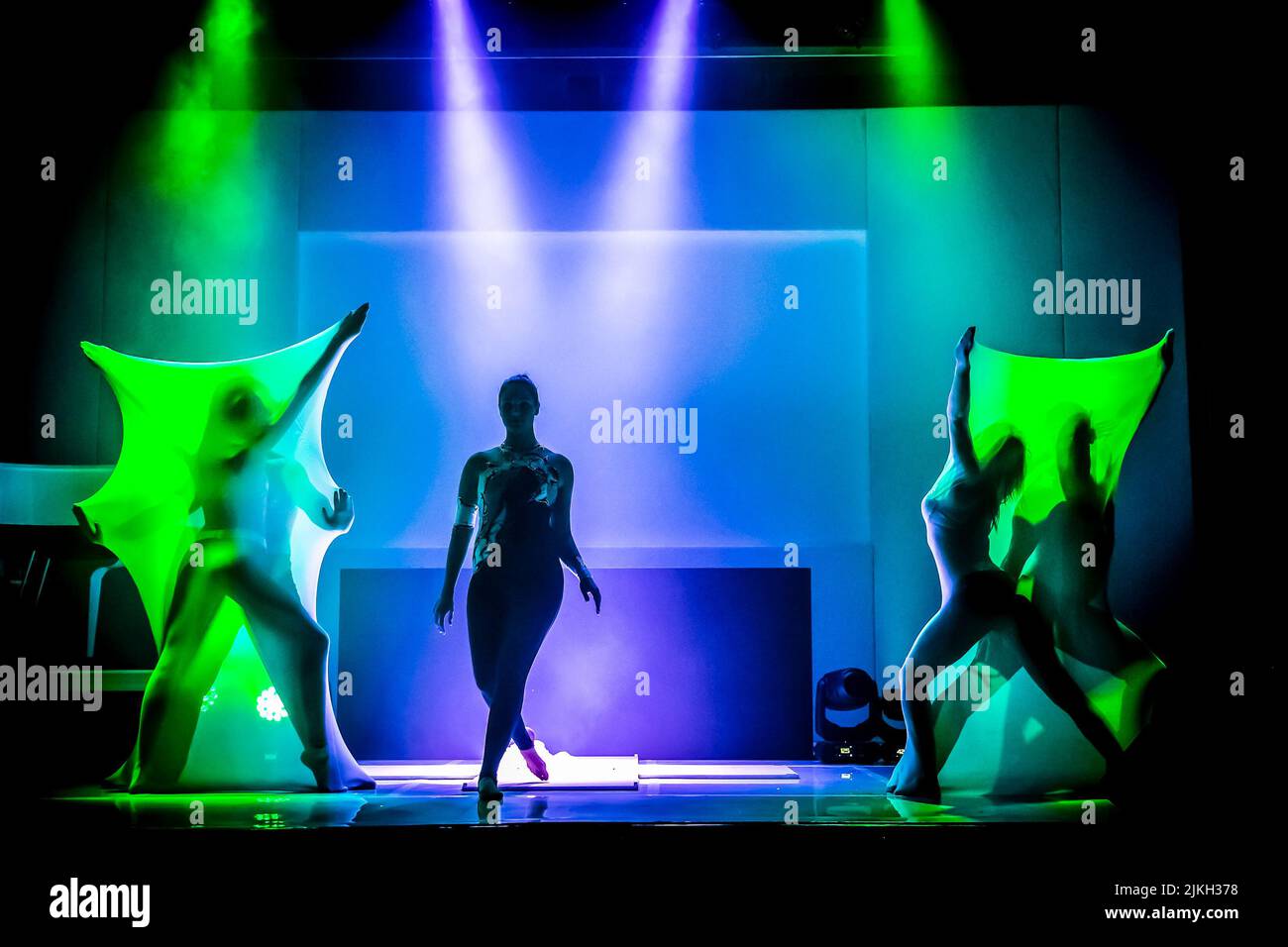 The contemporary dancers on an illuminated stage at a party event in