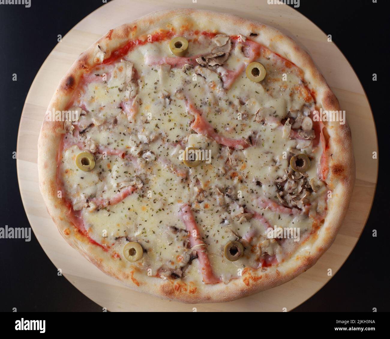 A top view of a pizza with mortadella, olives, mushroom and cheese