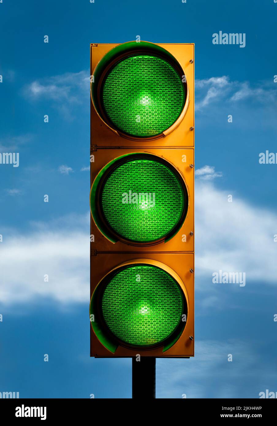 A vertical closeup shot of a traffic light with all green lights against the blue sky Stock Photo