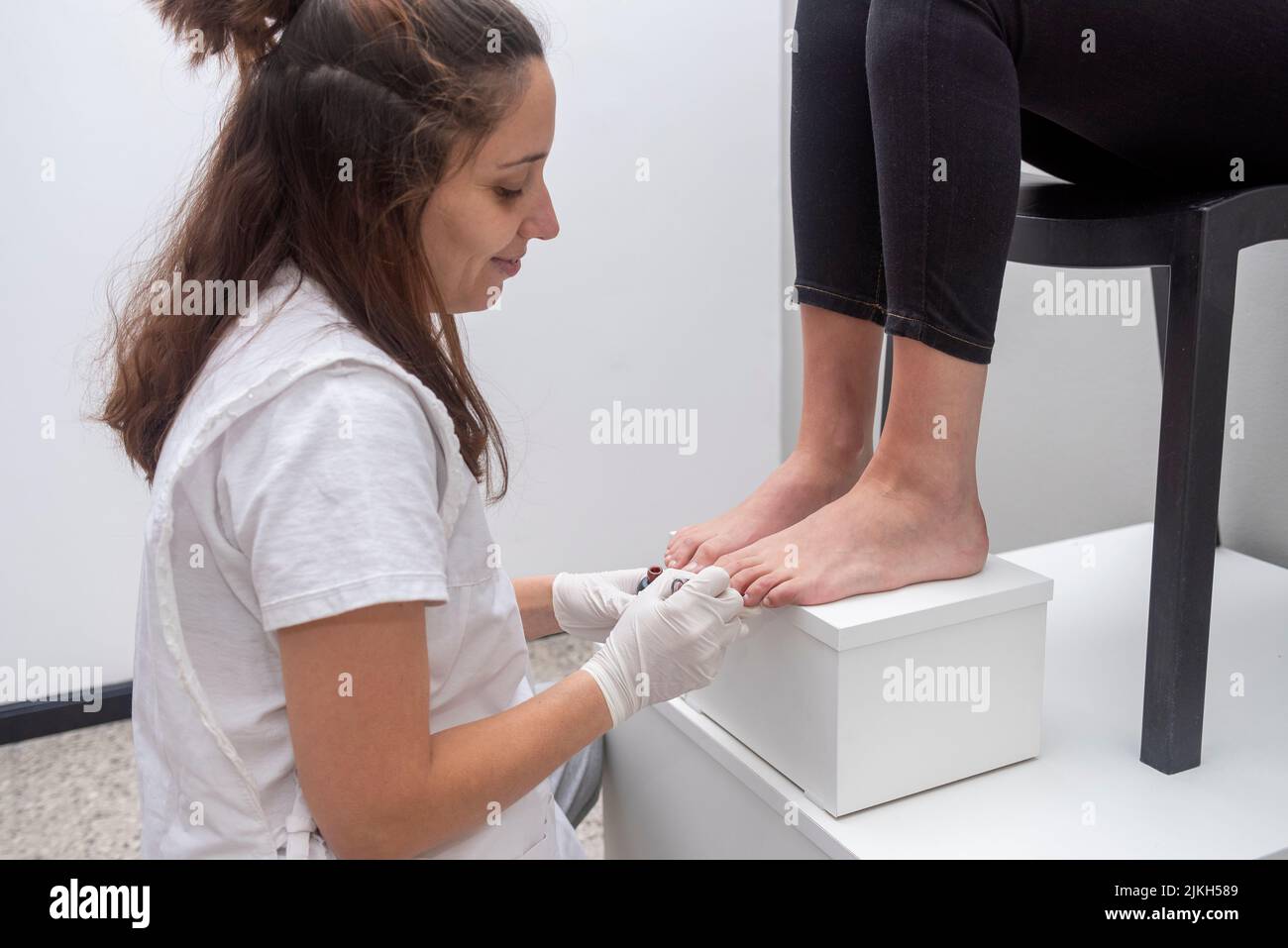 A female performing podiatry treatment in an aesthetic center Stock Photo