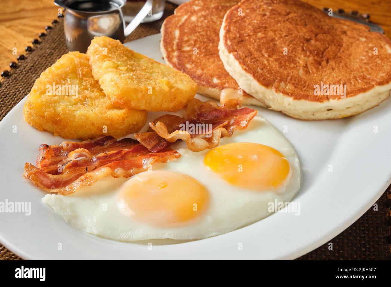 A closeup shot of an American breakfast with pancakes, eggs, hash brown and bacon Stock Photo