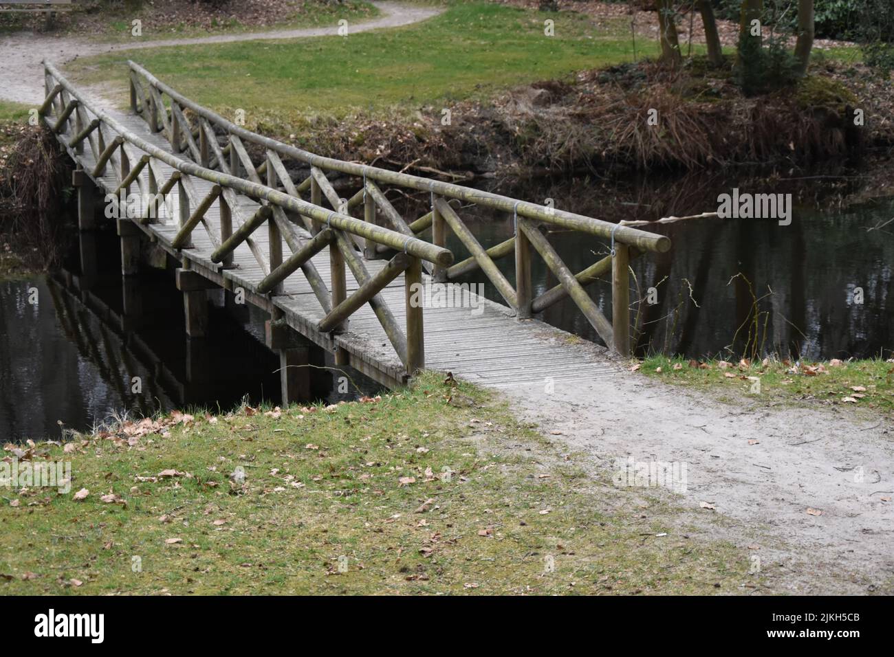 A small wooden bridge over a polluted river Stock Photo