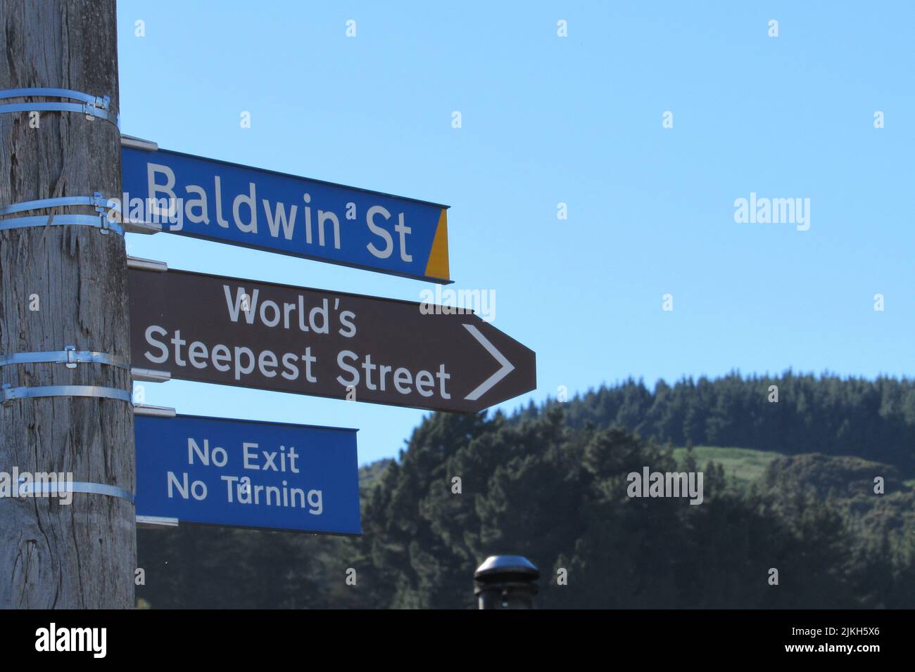 A closeup of a post with road signs of Baldwin Street, New Zealand in Dunedin Stock Photo
