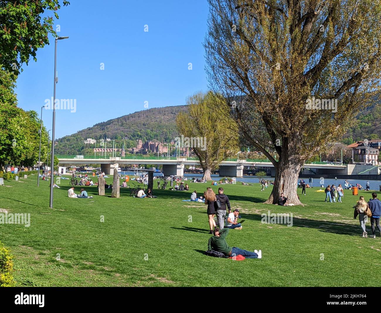 A beautiful shot of a park with people resting and walking next to Neckar river in Germany Stock Photo
