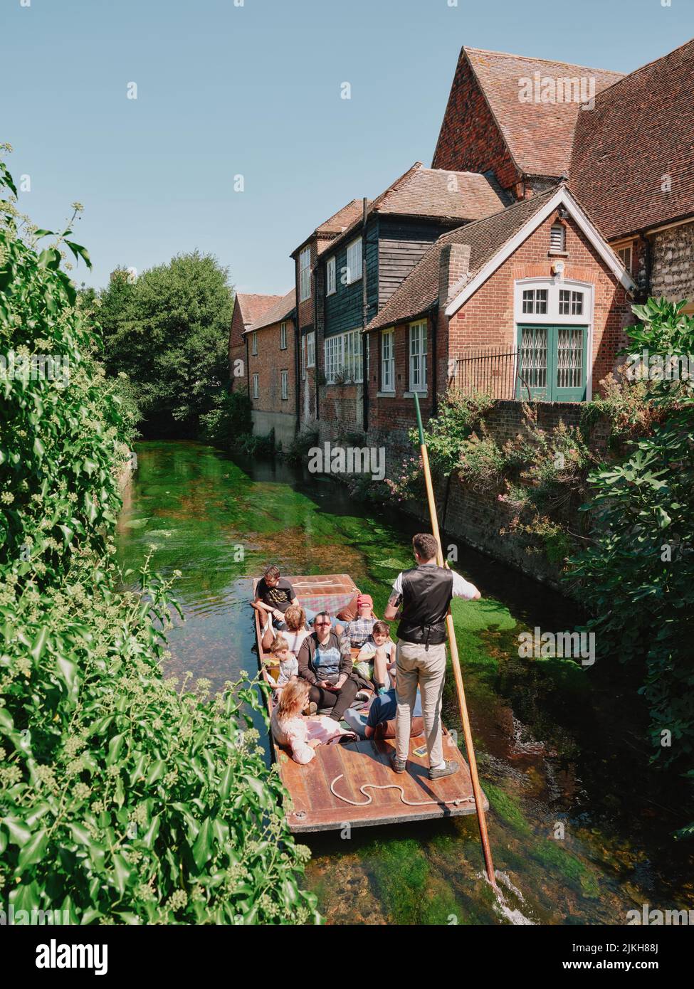 Summer tourists visitiors enoying a punt boat tour along the river Stour through the centre of old Canterbury Kent England UK - tourism punting summer Stock Photo