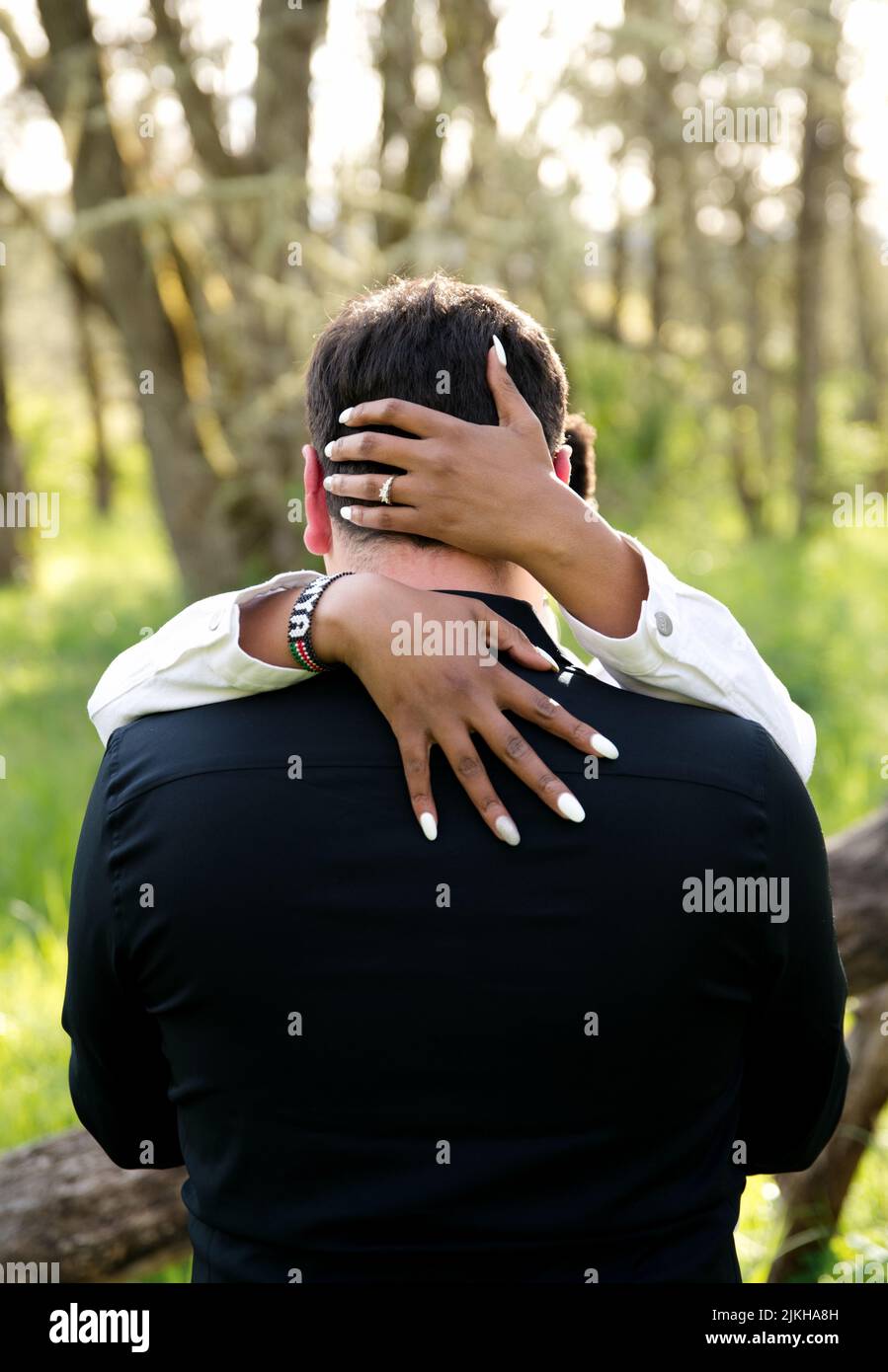 A vertical shot of a cute couple hugging each other outdoors during the engagement shoot Stock Photo