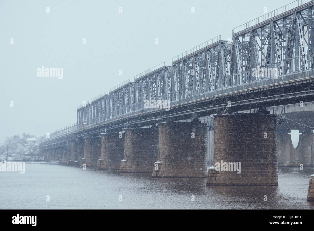 A beautiful view of a bridge over the lake on a cold winter snowy day ...