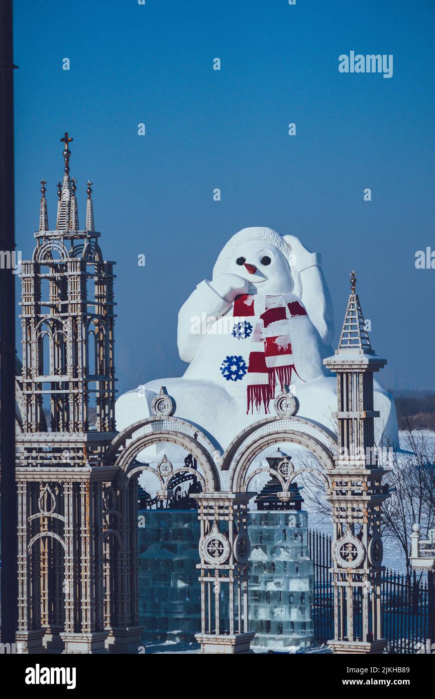 A Gigantic snowman next to the Ulmer Munster Church in Ulm, Germany under a blue sky Stock Photo