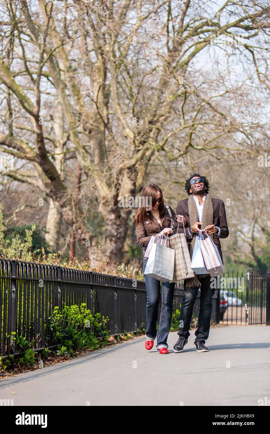 London shoppers; laugh out loud. A natural moment from young mixed race couple walking home after a day out shopping. From a series of images. Stock Photo
