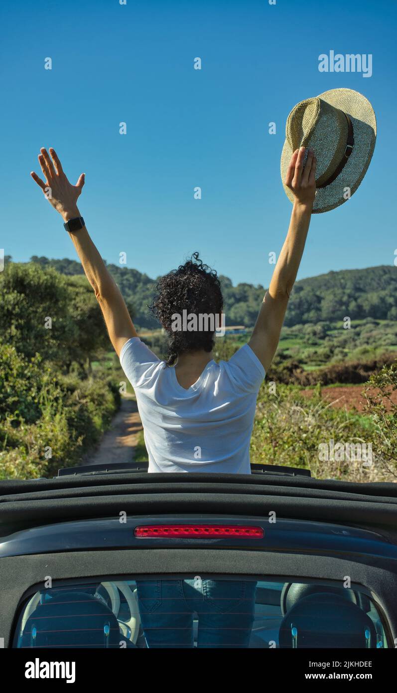 Woman feeling free in nature on a sunny day, in an attitude of victory. Wellness, summertime, travel and vacation concept. Vivid blue sky and copy spa Stock Photo