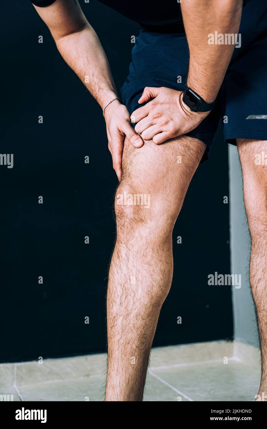 A vertical closeup of a Caucasian male athlete rubbing his right leg in