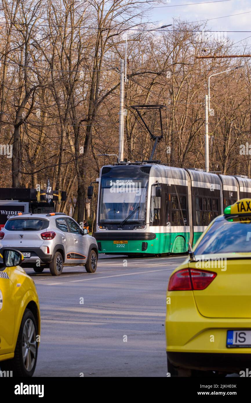 A vertical shot of public transportation - tram and cars in the street of Iasi, Romania Stock Photo