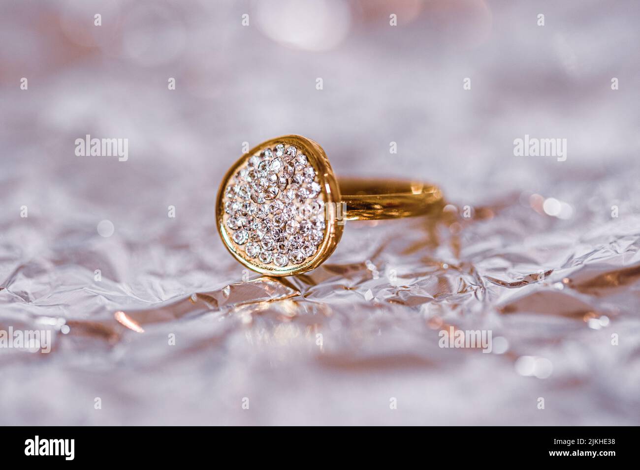 A closeup of golden diamond ring on shiny foil surface Stock Photo - Alamy