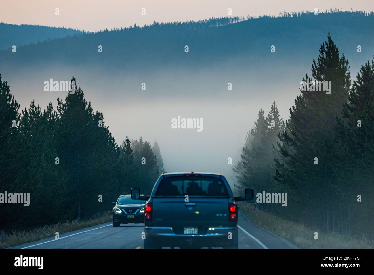 A pickup truck on a foggy road at the Yellowstone National Park Stock Photo