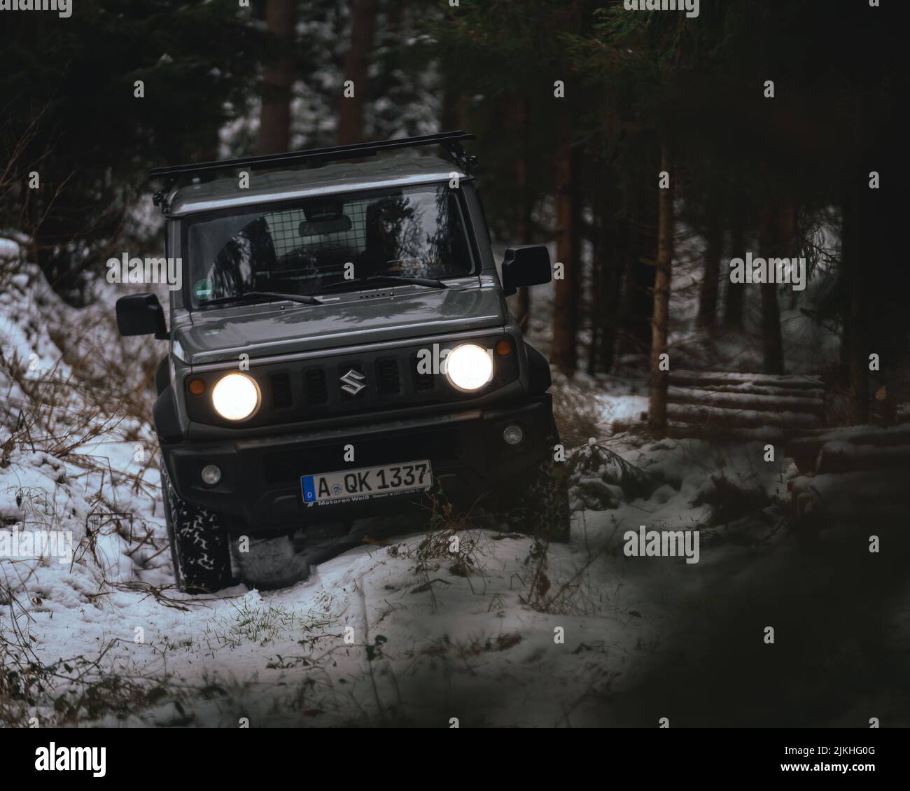 A black Suzuki Jimny driving through the woods in winter Stock Photo