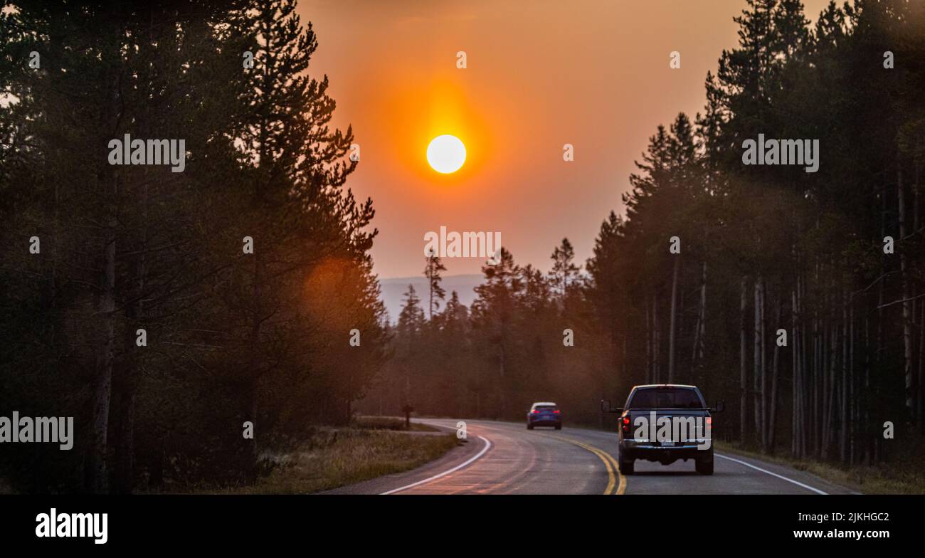 A pickup truck driving on a road at the Yellowstone National Park at sunrise Stock Photo