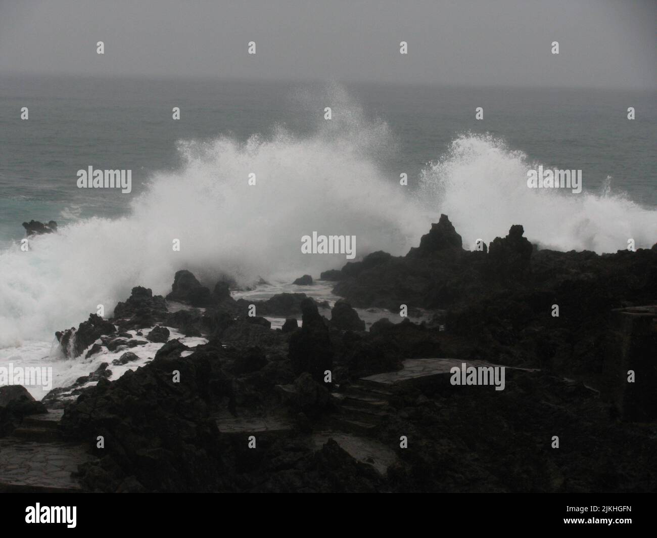 A beautiful shot of large splashing waves on a rocky shore Stock Photo ...