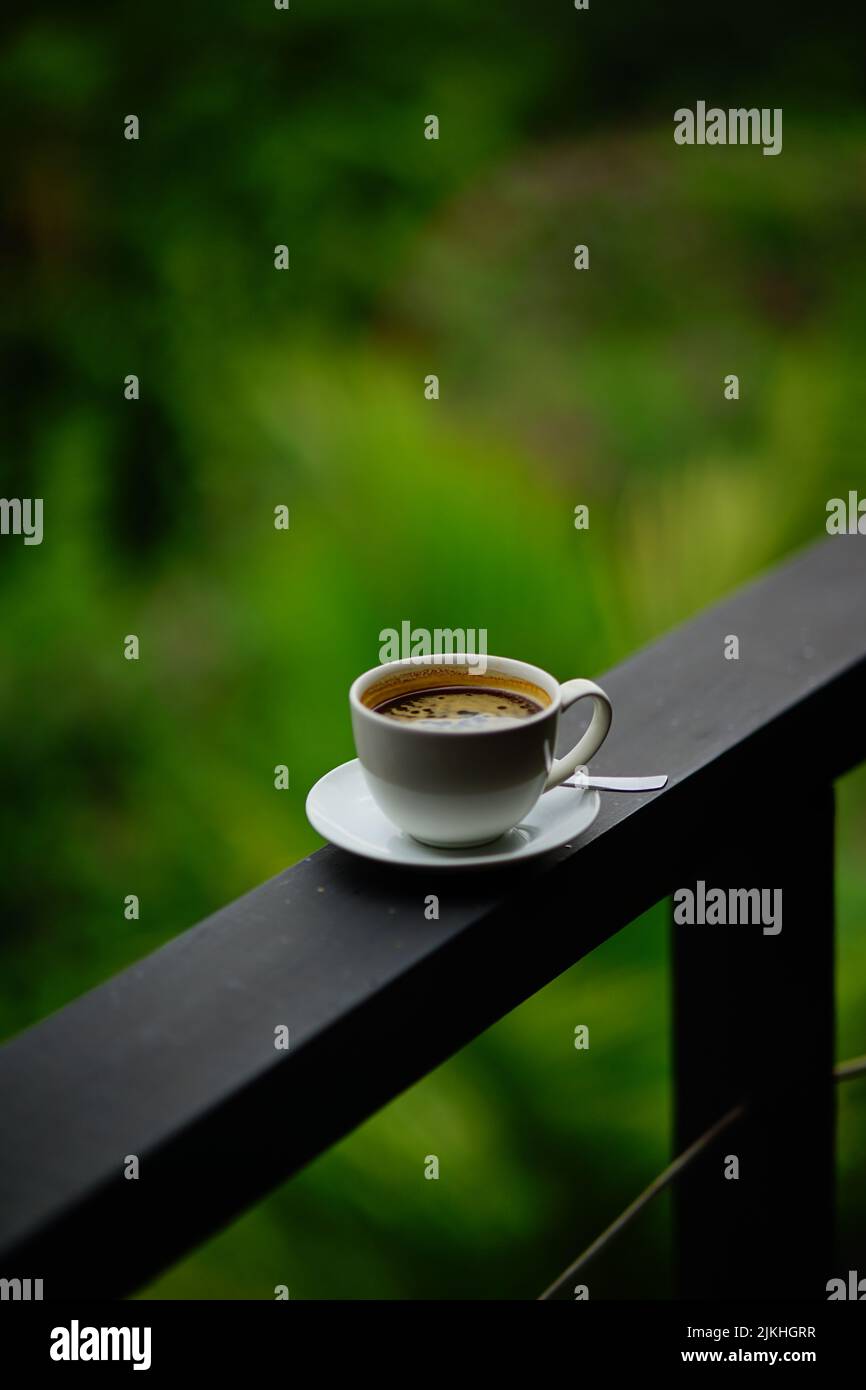 A cup of coffee on black balcony railing top Stock Photo - Alamy