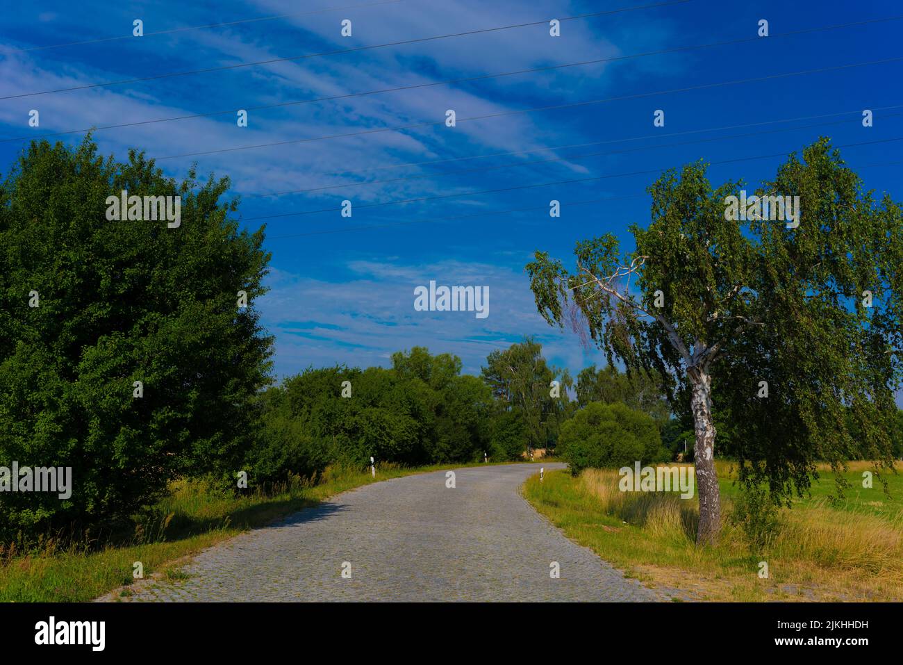 Paved country road in summer in Germany, few clouds in the sky Stock Photo