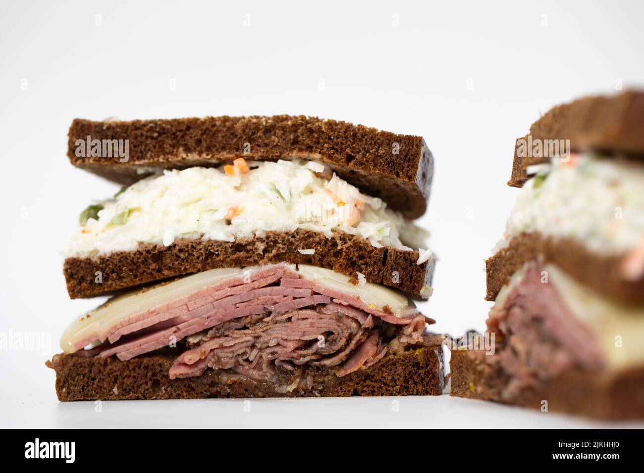 A pastrami sandwich sliced in half portraying all of its ingredients on a white background Stock