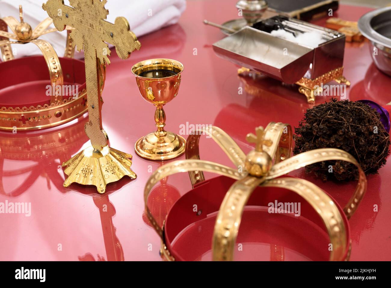 A golden cross, crowns, chalice, and a casket on a red church table