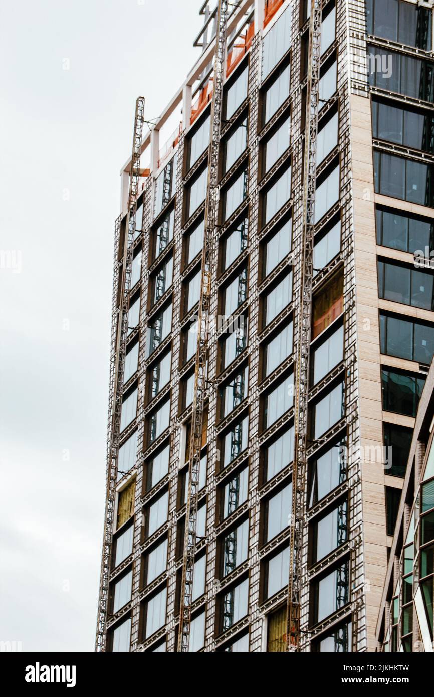 A vertical shot of the exterior of a constructing building in the daytime. Stock Photo
