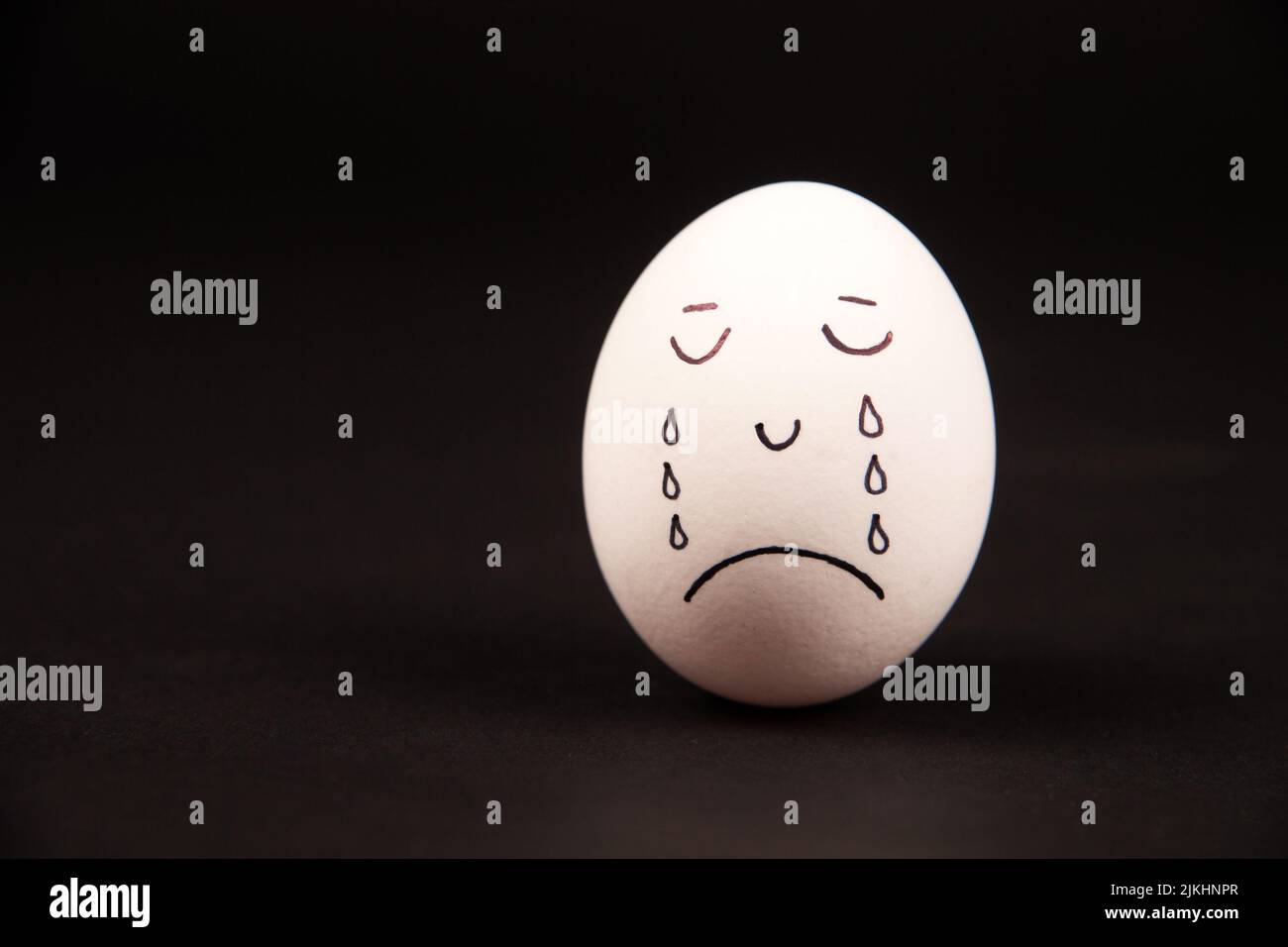 A closeup of a painted egg with a funny face on a black background Stock Photo