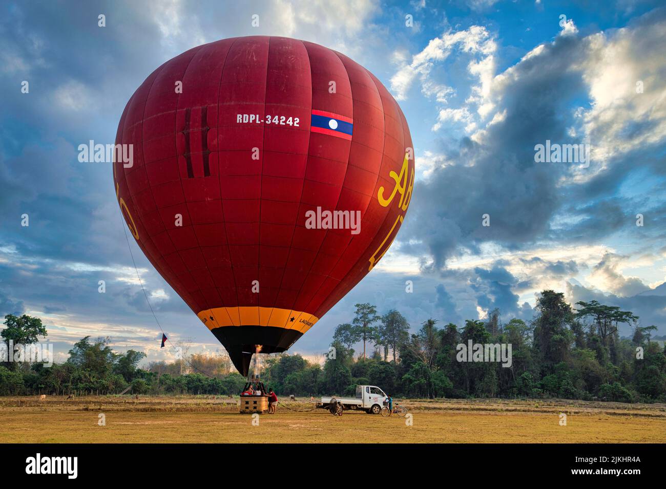 A large, red hot air balloon  with the flag of Laos preparing for a flight in Vang Vieng Stock Photo
